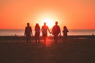 silhouette photo of five person walking on seashore during golden hour by Kevin Delvecchio courtesy of Unsplash.