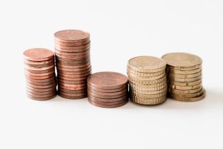 stacked round gold-colored coins on white surface by Ibrahim Rifath courtesy of Unsplash.