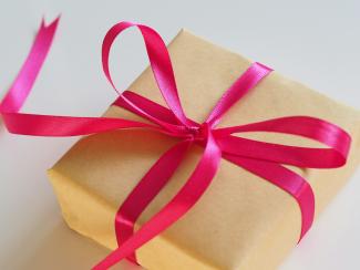 brown gift box with pink ribbon by Jess Bailey courtesy of Unsplash.