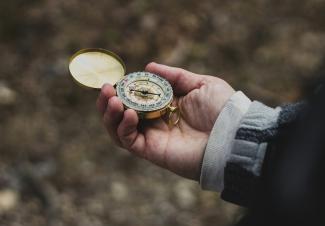 person using white and gold compass by Ethan Sykes courtesy of Unsplash.