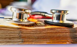 a stethoscope on top of a stack of money by Marek Studzinski courtesy of Unsplash.